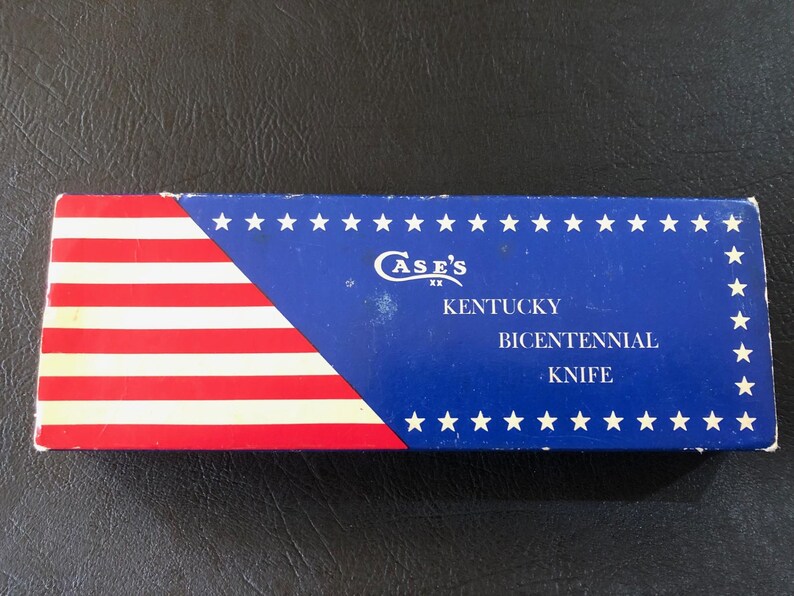 May include: Rectangular box with a patriotic design. The left side features red and white stripes, while the right side is blue with white stars. Text on the box reads "Case's Kentucky Bicentennial Knife."