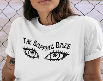 May include: White t-shirt with black text that reads "The Sapphic Gaze" and a graphic of two stylized eyes.
