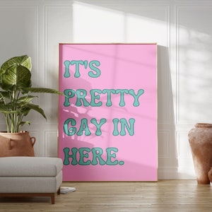 May include: A pink poster with the text "IT'S PRETTY GAY IN HERE." in teal lettering.