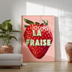 K&ouml;nnte beinhalten: Ein rosa Poster mit einer gro&szlig;en roten Erdbeere und dem Text "LA FRAISE" in gr&uuml;nen Buchstaben.