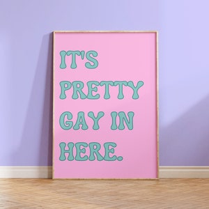 May include: A pink framed poster with the text "It's Pretty Gay In Here." in teal lettering.