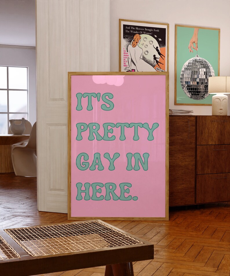 May include: A pink and green poster with the text "IT'S PRETTY GAY IN HERE." in a retro font.