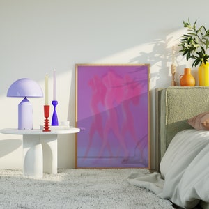May include: A white table with three candlesticks and a purple lamp. The candlesticks are red and blue. The lamp has a white shade. There is a framed picture of two figures in a purple and pink color scheme behind the table.