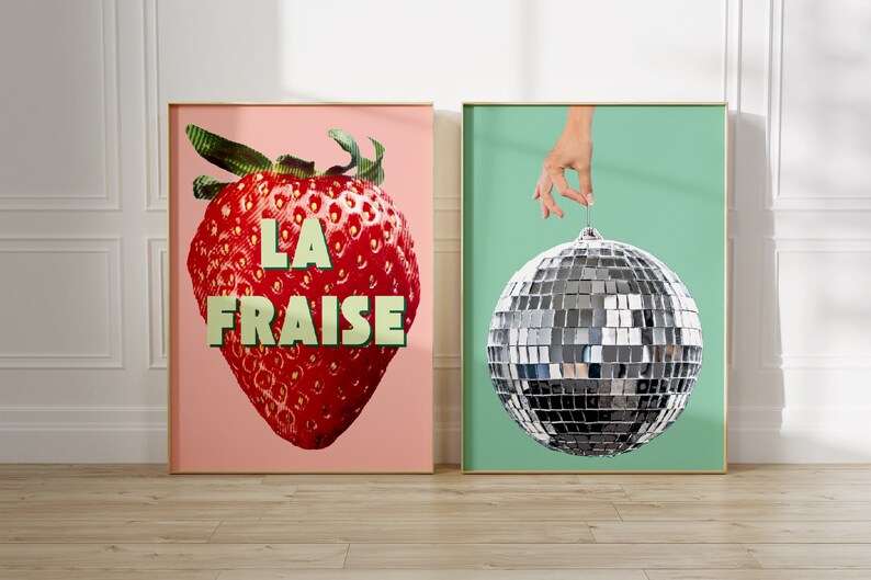 K&ouml;nnte beinhalten: Zwei gerahmte Drucke, einer mit einer roten Erdbeere mit dem Text "LA FRAISE" auf rosa Hintergrund und der andere mit einer silbernen Discokugel, die an einer Hand an einem hellgr&uuml;nen Hintergrund h&auml;ngt.