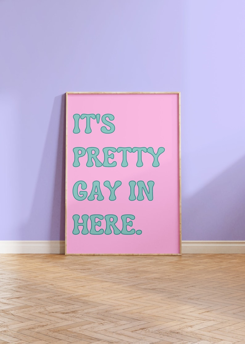 May include: A pink framed poster with the text "It's Pretty Gay In Here." in teal lettering.
