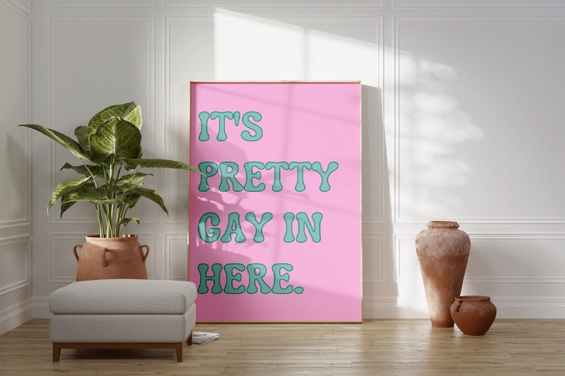 May include: A pink poster with the text "IT'S PRETTY GAY IN HERE." in teal lettering.
