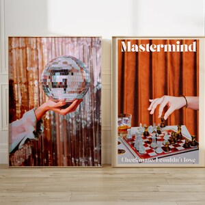 May include: Two framed posters with a retro aesthetic. The left poster features a hand holding a disco ball against a shimmering background. The right poster features a hand reaching for a chess piece on a chessboard with the text "Mastermind" and "Checkmate. I couldn't lose."