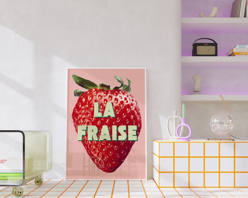 K&ouml;nnte beinhalten: Ein rosa Poster mit einer roten Erdbeere und dem Text "LA FRAISE" in gr&uuml;nen Buchstaben.