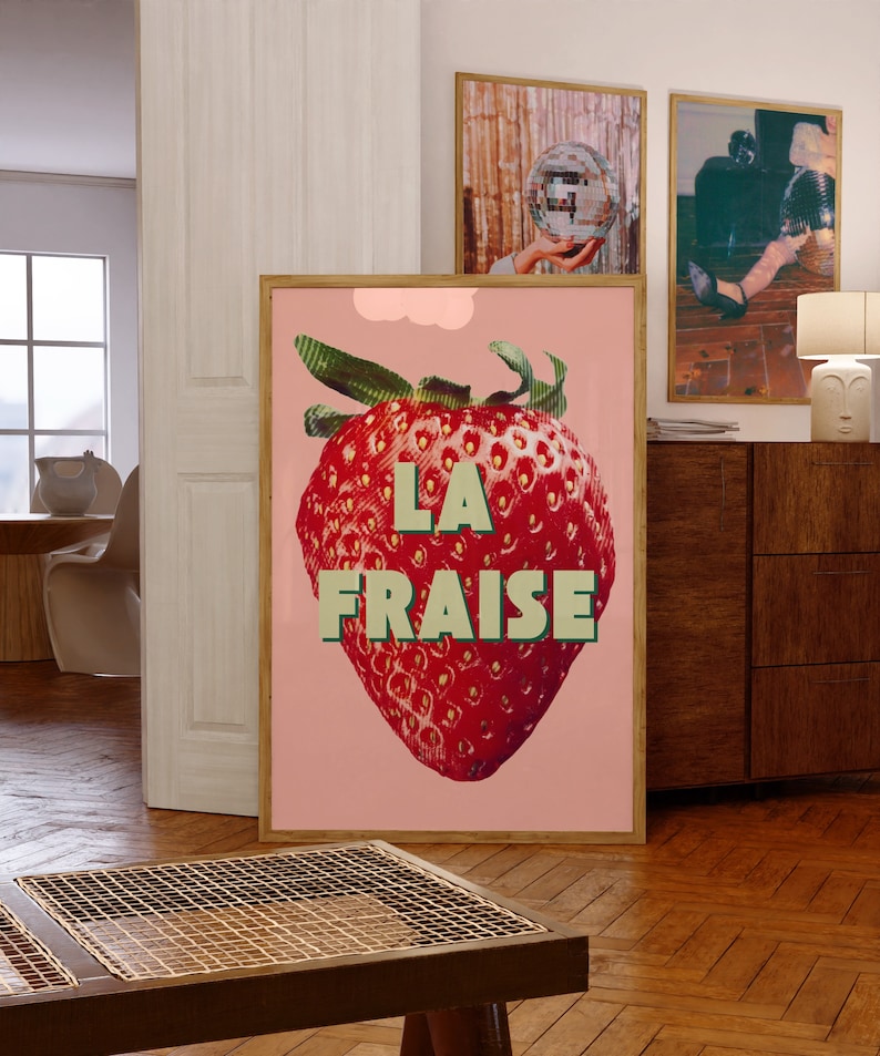 K&ouml;nnte beinhalten: Ein rosa Poster mit einer gro&szlig;en roten Erdbeere und dem Text "LA FRAISE" in gr&uuml;nen Buchstaben.