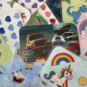 K&ouml;nnte beinhalten: Eine Sammlung bunter Aufkleber mit verschiedenen Designs, darunter ein Monstertruck, ein Einhorn, ein Regenbogen, ein Dinosaurier und ein Schiff. Die Aufkleber sind perfekt, um jedem Projekt einen Hauch von Fantasie zu verleihen.