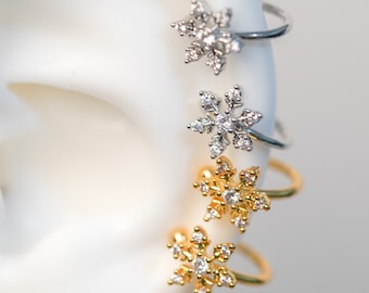 May include: Four snowflake ear cuffs in silver and gold with clear cubic zirconia stones. The ear cuffs are shown on a white mannequin head.