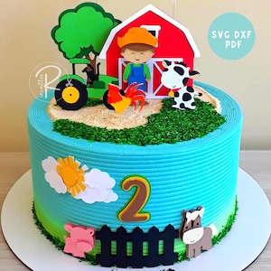 Puede incluir: Un pastel de dos pisos azul y verde decorado con recortes de animales de granja y con temática de granja. El pastel está decorado con un granero rojo, un tractor, una vaca, un gallo, un cerdo, un caballo, una cerca, un sol, nubes y el número "2". El pastel está sobre una base de pastel blanca. El texto "SVG DXF PDF" está en un círculo azul en la parte superior derecha de la imagen.