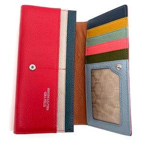 Könnte beinhalten: Ein mehrfarbiges Lederportemonnaie mit leuchtend roter Außenseite und silbernem Druckknopfverschluss. Das Innere zeigt verschiedene Kartenfächer in Marineblau, Gelb, Mint, Pink und Oliv sowie ein hellblaues Sichtfenster für Ausweise und Text.