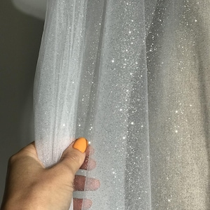 Tulle scintillant dans des tons de blanc avec des paillettes. Tissu léger pour robes de mariée, robes de soirée et accessoires de mariage