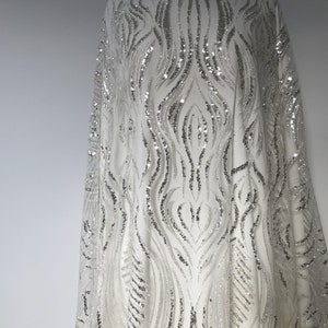 Una tela brillante con un patrón abstracto de ondas y lentejuelas espejadas. Perfecta para vestidos de noche, vestidos de novia y accesorios de novia.