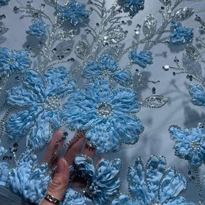 Spectacular lace with a floral motif, densely embroidered with shiny sequins, beads, and pearls. Fabric for evening dresses.