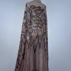 Pizzo da sera con decorazioni scintillanti. Il tessuto è decorato con perline e paillettes. Tessuto riccamente decorato per abiti da sera.