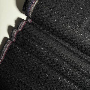 Italian fabric with a shiny thread. Sewing fabric, garment fabric. Substantial black material for jackets, skirts, and coats.