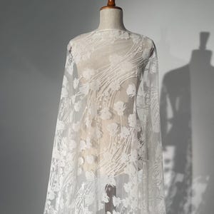 Una tela brillante con motivos florales sobre un reverso de malla suave. Este brocado es perfecto para vestidos de noche, vestidos de novia y accesorios de novia.