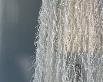 Feather lace in off-white adorned with sequins. Each element is hand-sewn. Perfect for a wedding gown.