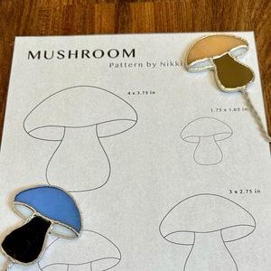 Peut inclure: Un modèle imprimable pour réaliser des ornements en vitrail en forme de champignons. Le modèle comprend quatre tailles différentes de champignons, avec des mesures en pouces. Le texte sur la page indique "Mushroom Pattern by Nikki" et "Veuillez ne pas partager ou reproduire ce modèle. Vous pouvez vendre votre pièce finie comme vous le souhaitez ! Identifiez-nous sur instagram @nikki.glassworks :)"
