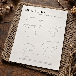 Peut inclure: Un patron en papier blanc intitulé MUSHROOM Pattern by Nikki Glass Works présentant quatre contours de champignons en ligne noire avec des dimensions en pouces : 4 x 3,75 in, 1,75 x 1,65 in, 3 x 2,75 in et 2,5 x 2,25 in, avec des instructions.