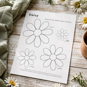 May include: A white paper sheet featuring a Daisy pattern by Nikki Glass Works with four black-outlined flower shapes. Dimensions are labeled as 5x5 in, 4x4 in, 3x3 in, and Mini 2x2 in. The text includes usage instructions and social media tags.