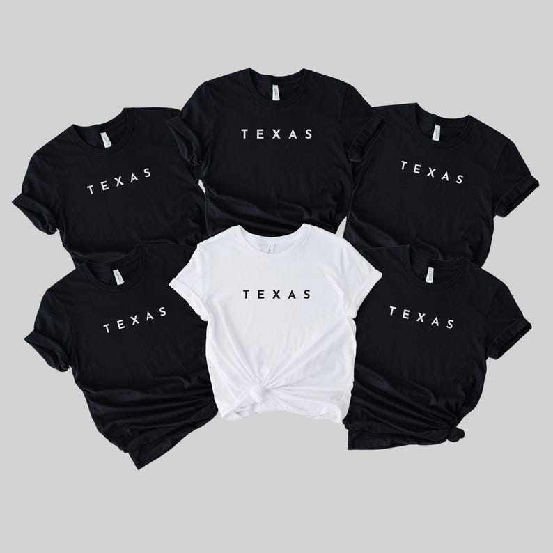 May include: Six t-shirts with the word "TEXAS" printed in white on a black background. One t-shirt is white with black text.