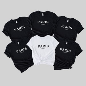 May include: Five t-shirts, four black and one white, with the text "PARIS FRANCE" printed on the front.
