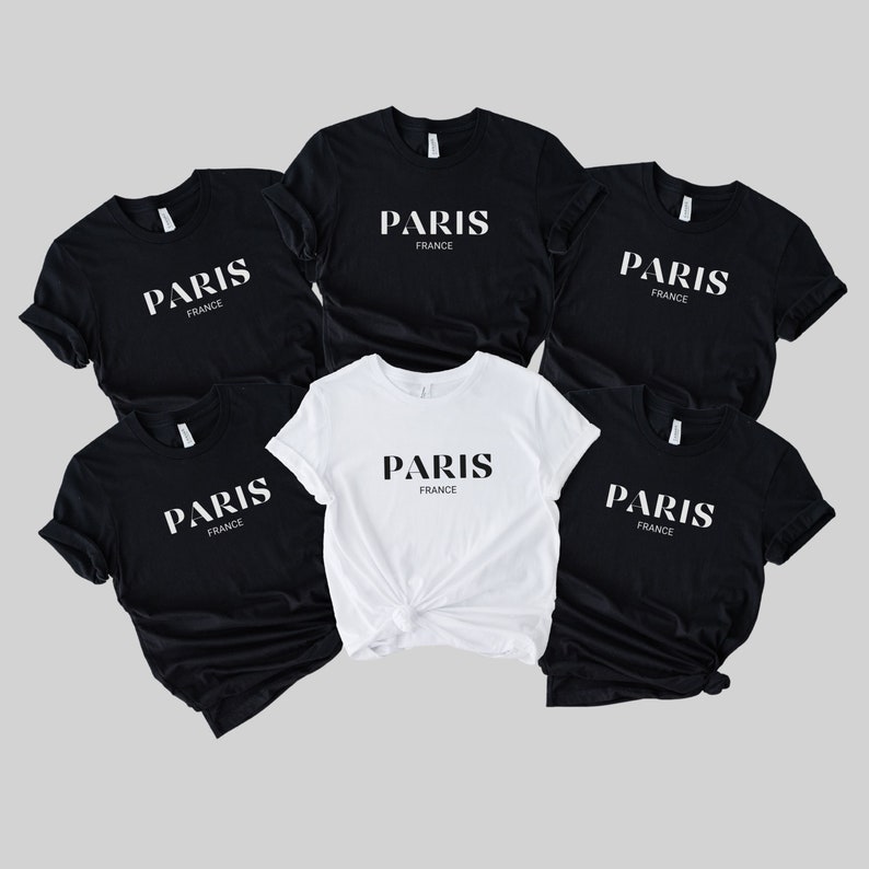 May include: Five t-shirts, four black and one white, with the text "PARIS FRANCE" printed on the front.
