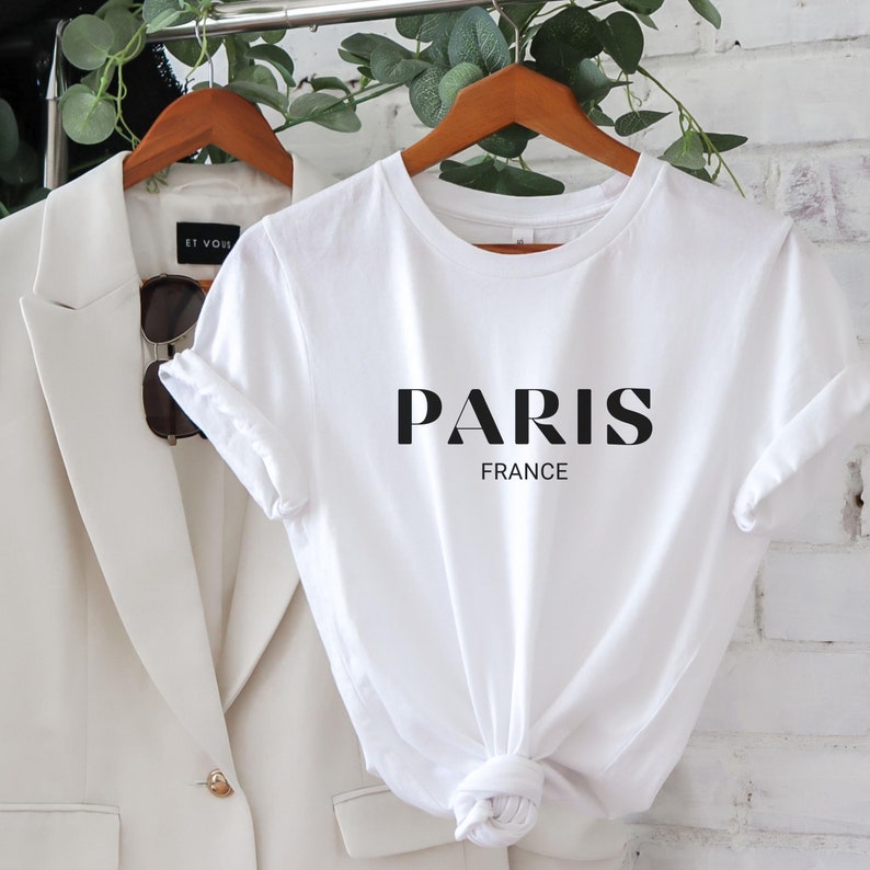 May include: White t-shirt with black text that reads "PARIS FRANCE" on a white background.