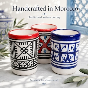 Peut inclure: Trois tasses cylindriques en céramique avec des motifs peints à la main. L'une présente des motifs géométriques noirs, une autre des motifs floraux rouges et bleus, et la troisième des motifs linéaires bleus. Texte : Handcrafted in Morocco.