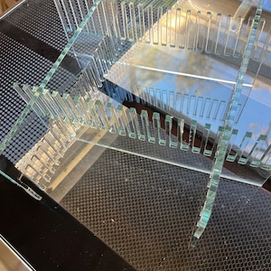 Puede incluir: Un organizador de acrílico transparente con múltiples compartimentos. El organizador está diseñado para contener artículos como utensilios, bolígrafos u otros objetos pequeños.