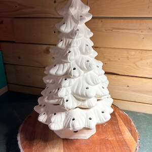 Puede incluir: Una figura de árbol de Navidad de cerámica blanca con un diseño de ramas escalonadas y texturizadas, que presenta numerosos orificios circulares pequeños y uniformemente espaciados para iluminación o adornos.