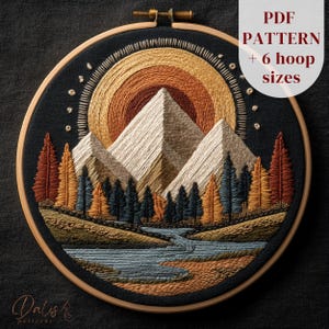 May include: Embroidered landscape art in a wooden hoop. The design features mountains, trees, and a river, with a sunset in the background. The color palette includes shades of brown, orange, blue, and cream. Text on the image reads "PDF PATTERN + 6 hoop sizes."