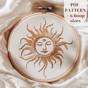 Puede incluir: Diseño de sol bordado en un bastidor de madera. El sol es dorado con un rostro y detalles de estrella. El texto "PDF PATTERN + 6 hoop sizes" es visible. El diseño está sobre tela color crema.