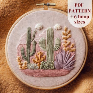 May include: Embroidered desert landscape in a wooden hoop. The design features cacti, succulents, and clouds in shades of green, pink, and tan. The text "PDF PATTERN + 6 hoop sizes" is visible.