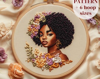 May include: Embroidered hoop art featuring a woman with dark brown skin and curly black hair, adorned with a floral wreath. The flowers are in shades of yellow, orange, pink, and purple. The background is a light beige fabric.