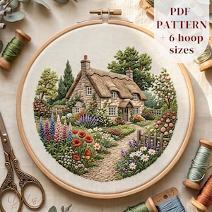 May include: An embroidery hoop containing a fabric panel with a detailed stitched scene of a stone cottage with a thatched roof, surrounded by a vibrant garden of lupines, poppies, and daisies. The text PDF PATTERN + 6 hoop sizes is visible.