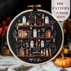 Könnte beinhalten: Ein besticktes Halloween-Themen-Hoop-Art-Stück. Das Design zeigt einen schwarzen Hintergrund mit drei Holzregalen, die Bücher, Kerzen, Geister und andere gruselige Elemente halten. Der Text "PDF PATTERN + 6 hoop sizes" ist sichtbar. Die Stickerei ist in verschiedenen Farben.