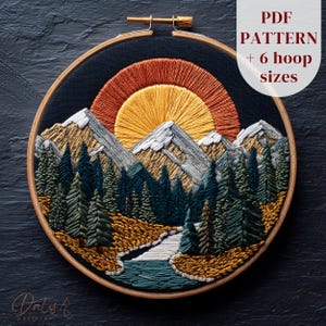 May include: An embroidered landscape scene in a wooden hoop. The design features a sunset with orange and yellow hues, snow-capped mountains, a river, and evergreen trees. Text on the image reads "PDF PATTERN + 6 hoop sizes".