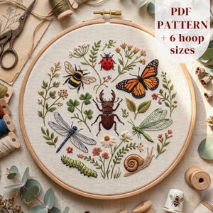 May include: An embroidery hoop containing a fabric panel with stitched insects including a ladybug, bumblebee, monarch butterfly, stag beetle, dragonfly, green insect, caterpillar, and snail, surrounded by floral stems. Text reads PDF PATTERN + 6 hoop sizes.
