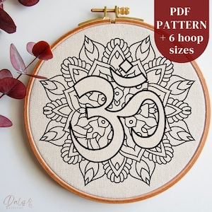 May include: A black and white embroidery pattern of the Om symbol surrounded by a mandala design. The pattern is displayed on a beige fabric in a wooden embroidery hoop. The text "PDF PATTERN + 6 hoop sizes" is displayed in the upper right corner of the image.