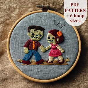 Può includere: Un telaio da ricamo circolare in legno contenente un tessuto azzurro con un disegno cucito a mano di due figure che si tengono per mano. Il testo PDF PATTERN + 6 hoop sizes è visibile nell'angolo in alto a destra.