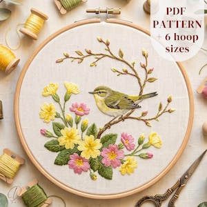 May include: An embroidery hoop containing a fabric panel with a stitched design of a yellow bird perched on a branch surrounded by yellow and pink flowers. The text PDF PATTERN + 6 hoop sizes is visible in the upper right corner of the image.