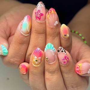 May include: A close-up of a hand with long, almond-shaped nails. Each nail features a unique design, including floral patterns, animal prints, and gradient colors. Some nails have pearl and gold accents, creating a vibrant and artistic manicure.