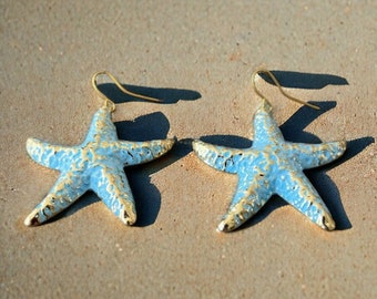 May include: A pair of blue and gold starfish earrings. The starfish are textured and have a metallic finish.