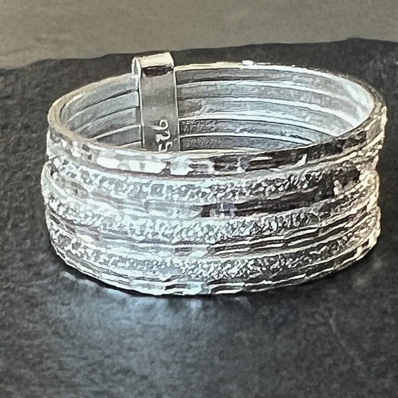 May include: Silver ring with a textured, layered design. The ring is marked with the number "526".