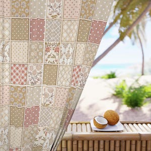 May include: A patchwork curtain with a variety of patterns in beige, pink, and cream tones. The curtain is made up of squares with floral, polka dot, and geometric designs. A white plate with a halved coconut and a whole coconut sits on a bamboo table, with a beach scene in the background.