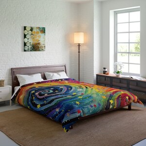 May include: A colorful duvet cover with a swirling rainbow design and stars on a dark blue background. The duvet cover is made of soft, comfortable fabric and is perfect for adding a touch of whimsy to any bedroom.